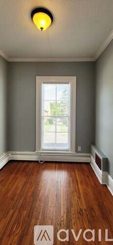 A room with a window and a wooden floor.