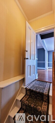 A hallway with a staircase leading to a bedroom.