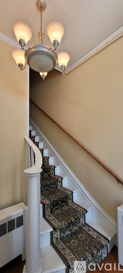 A chandelier hangs over a staircase with a white balustrade.