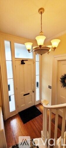 A chandelier hangs from the ceiling in a room with wooden floors and white walls.