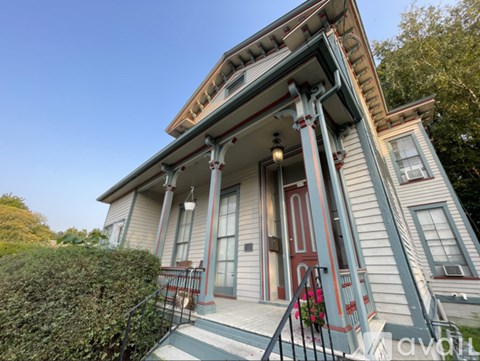 A house with a red door and a porch with a railing.
