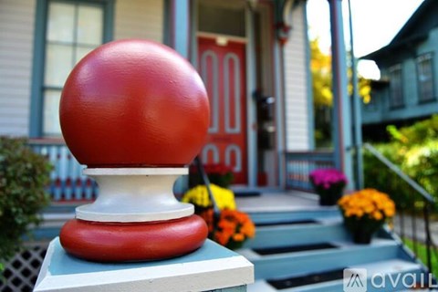 A red and white spherical object sits on a pedestal in front of a house.