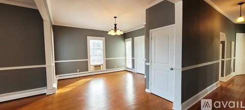 A large empty room with wooden floors and a chandelier hanging from the ceiling.