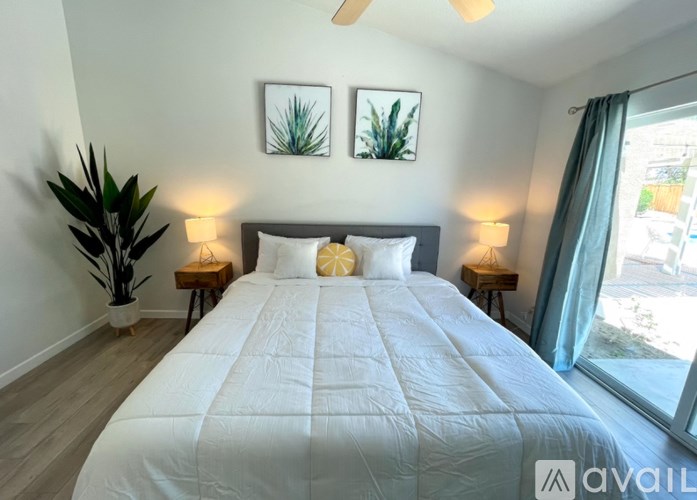 A bedroom with a large bed and two potted plants.