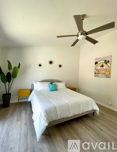 A bedroom with a white bed and a ceiling fan.