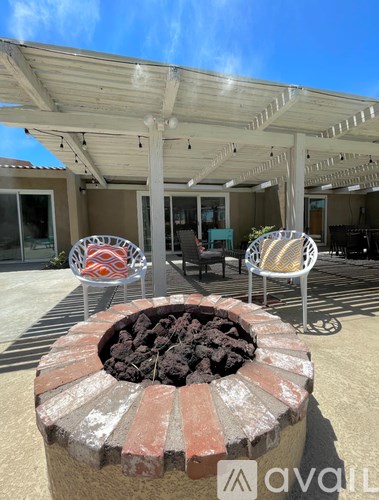 A patio with a fire pit and chairs.