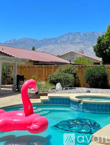 A pink flamingo float in a pool with mountains in the background.