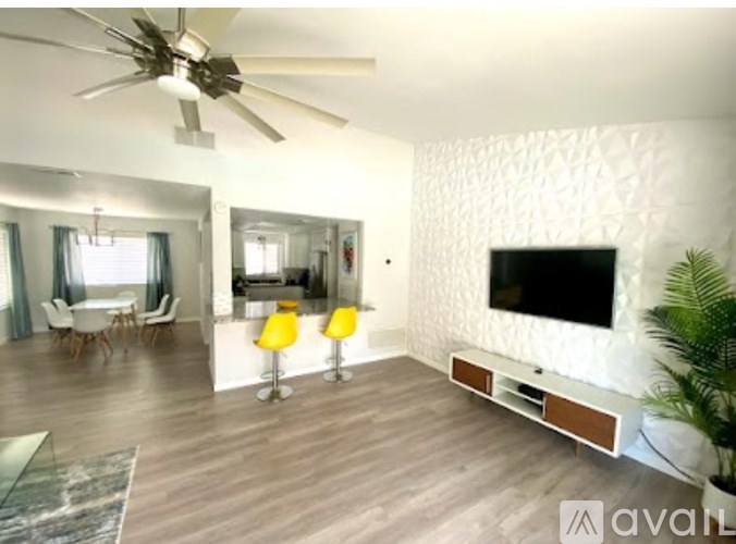 A living room with a television, a fan, and a dining table.