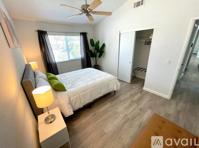 A bedroom with a bed, a ceiling fan, and a lamp.