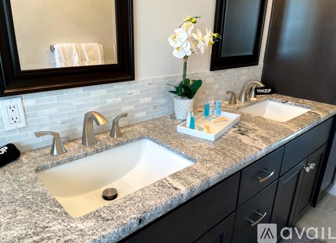 A bathroom with a granite countertop and a double sink.