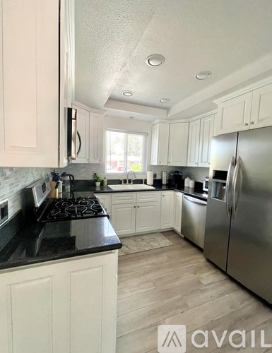 A kitchen with white cabinets and a black countertop.