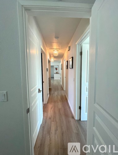 A long hallway with white walls and wood flooring.
