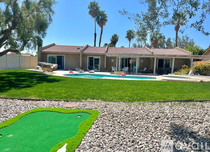 A house with a pool and a miniature golf course in the front yard.