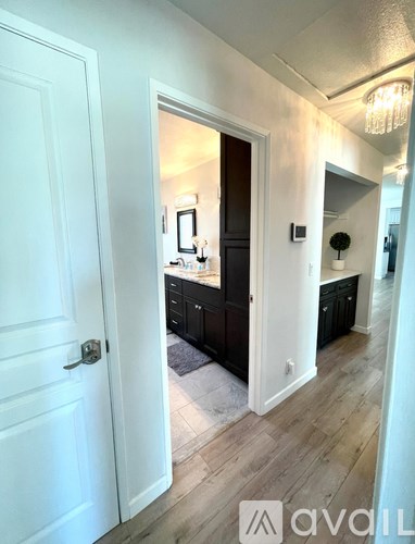 A white door opens to a dark room with a chandelier.