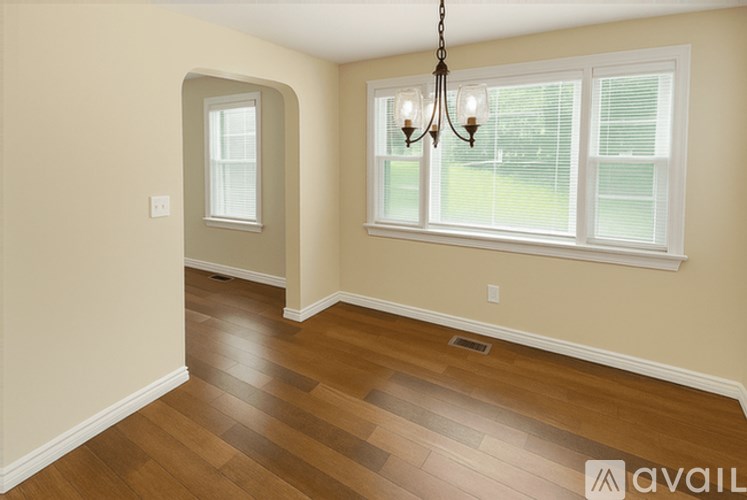 A room with a chandelier and a window with blinds.
