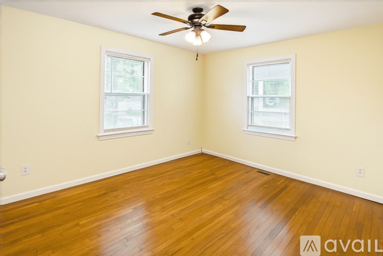 A room with wooden floors and two windows.