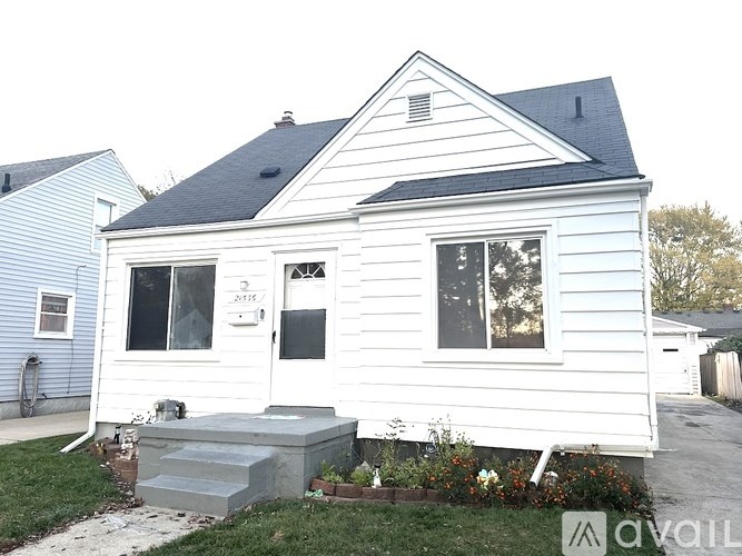 A white house with a black roof and a small front yard.