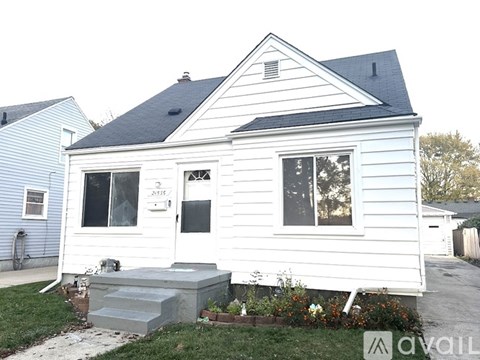 A white house with a black roof and a small front yard.