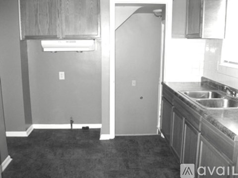 A black and white photo of a kitchen with a sink and a refrigerator.