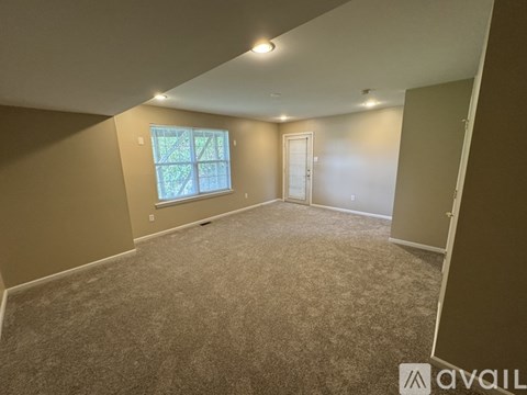 A room with a carpeted floor, a window, and a door.