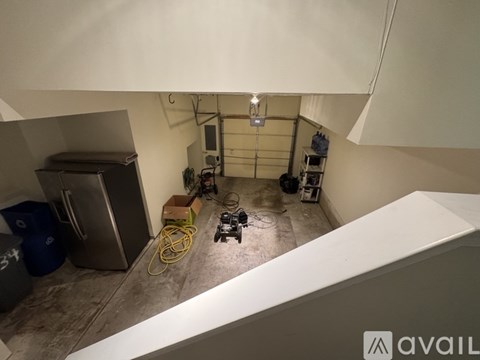 A room with a refrigerator, a yellow hose, and a black object on the floor.