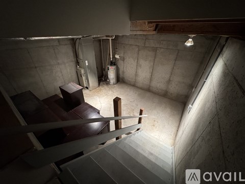 A staircase in a dimly lit basement with a metal railing.