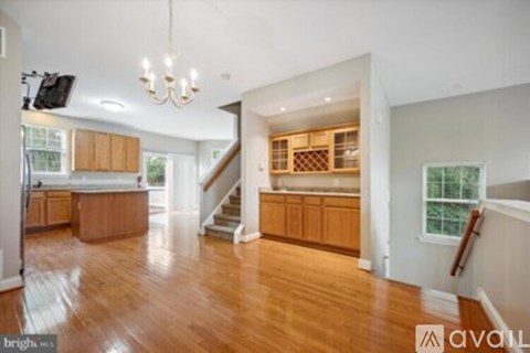 A spacious living room with wooden floors and a staircase leading to the upper level.
