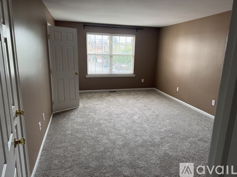 A room with a carpeted floor and a window with blinds.