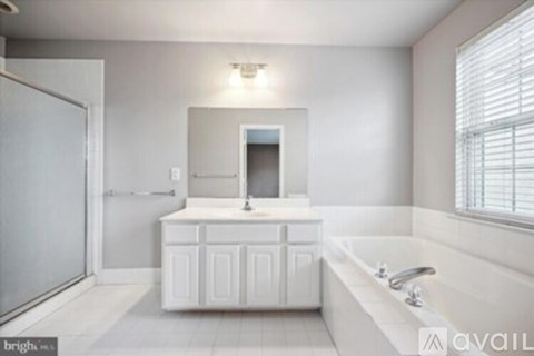 A white bathroom with a tub, sink, and mirror.