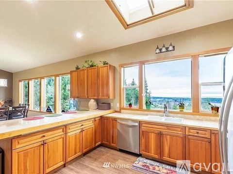 A kitchen with wooden cabinets and a large window overlooking the ocean.