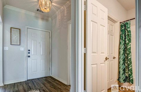 A hallway with a white door and a chandelier.
