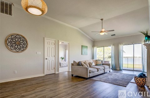 A living room with a couch, a rug, a ceiling fan, and a wall hanging.