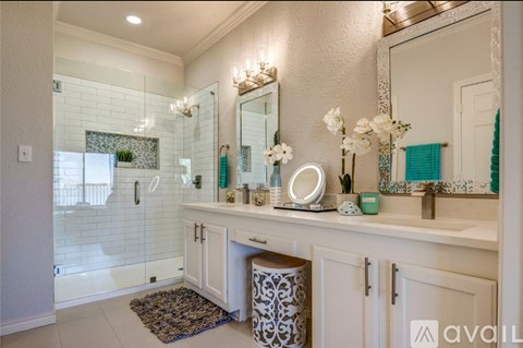 A bathroom with a white vanity, a mirror, and a shower area.