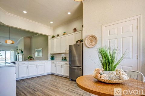 A kitchen with white cabinets and a wooden table with a plant on it.