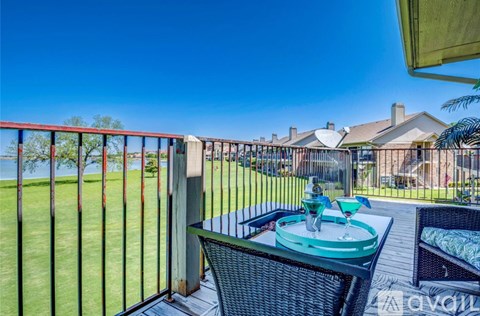 A patio with a table and chairs overlooking a grassy area.