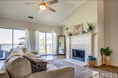 A living room with a couch, a fireplace, and a ceiling fan.
