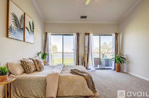 A bedroom with a large bed and a view of a balcony through the window.