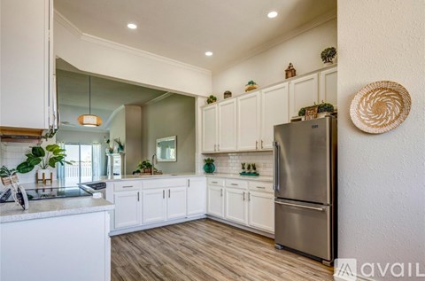 A kitchen with white cabinets and a stainless steel refrigerator.