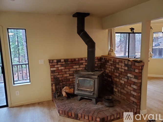 A wood stove is in a brick fireplace.