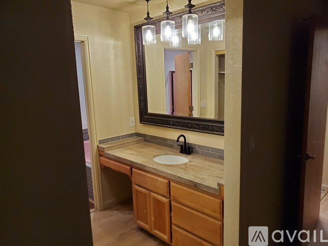 A bathroom with a sink, mirror, and wooden cabinets.