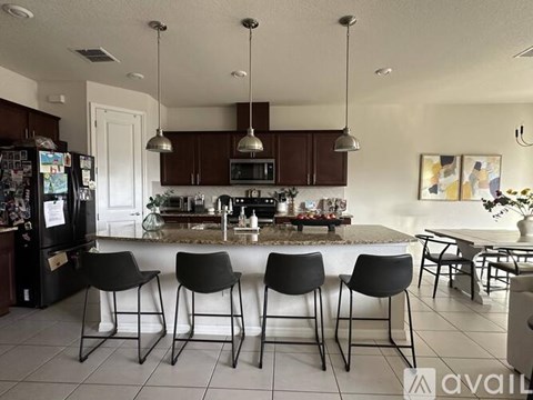 A kitchen with black chairs and a white fridge.