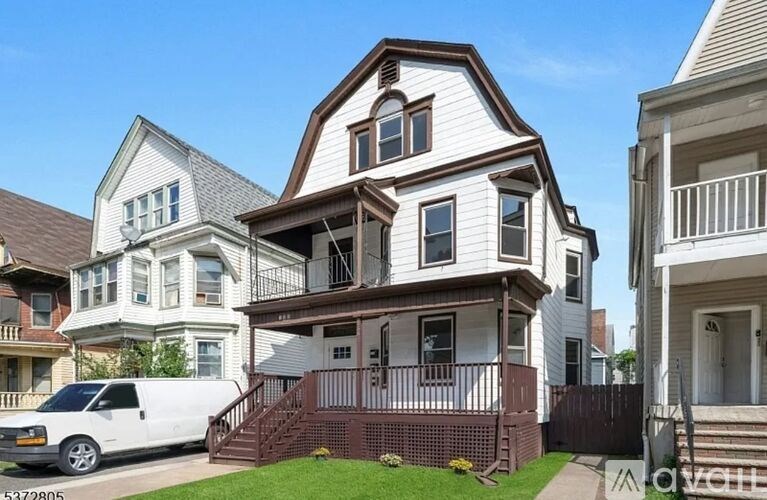 A white van is parked in front of a two-story house.