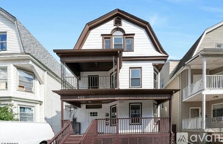 A white house with a balcony and a brown roof.