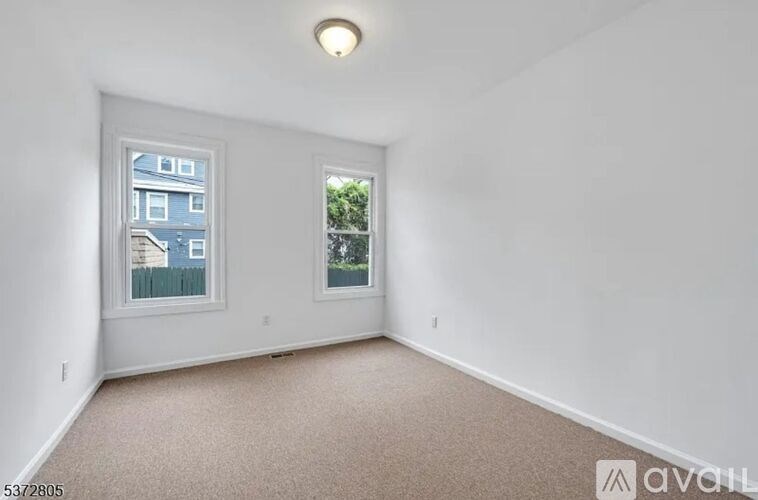 A room with a carpet floor and two windows.
