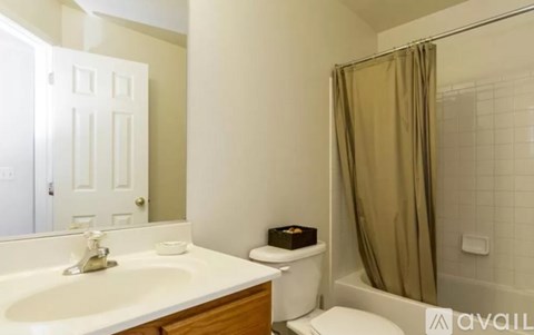 A bathroom with a white sink and a shower with a brown curtain.