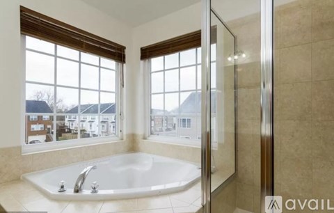 A bathroom with a large tub and a view of a residential area outside the window.