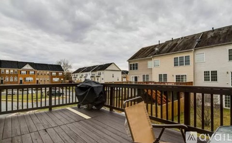 A balcony with a black umbrella and a brown chair.