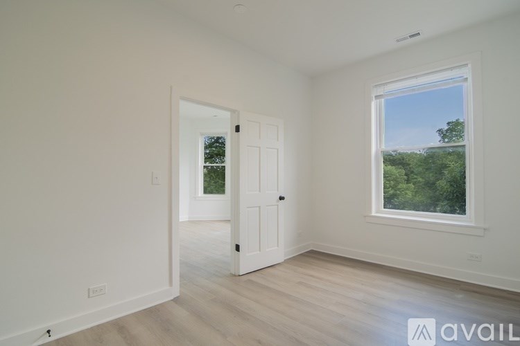 A room with a white door and a window overlooking a green landscape.