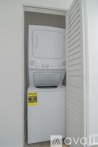 A white dryer is in a small closet.