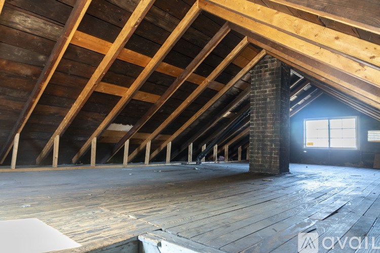 A room with wooden floors and ceiling, and a window on the right side.